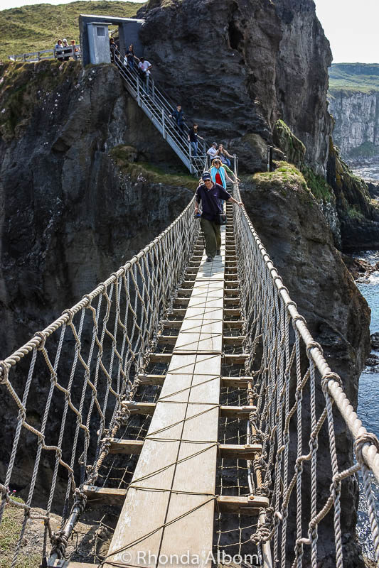 Walking across Carrick A Rede Rope Bridge in Northern Ireland. Often called the Giant's Causeway bridge, it is one of the most famous bridges in Ireland