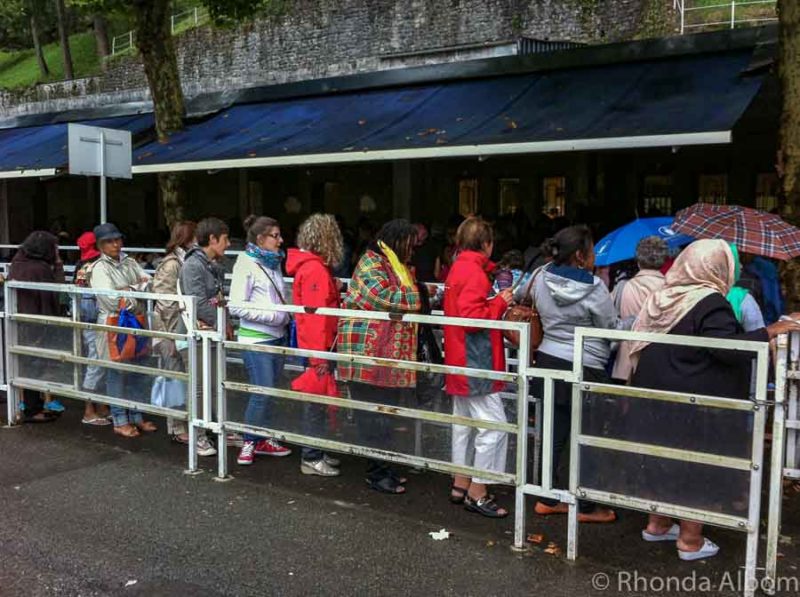 La coda delle donne per entrare nella grotta e immergersi nell'acqua curativa di Lourdes Francia's queue to enter the grotto and dip into the Lourdes healing water France