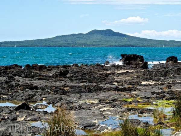 Volcanic rock in the foreground, with Rangitoto Volcano in the background