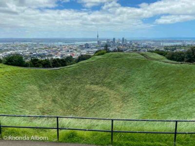 At the Mount Eden volcano summit overlooking the crater and the skyline of Auckland city