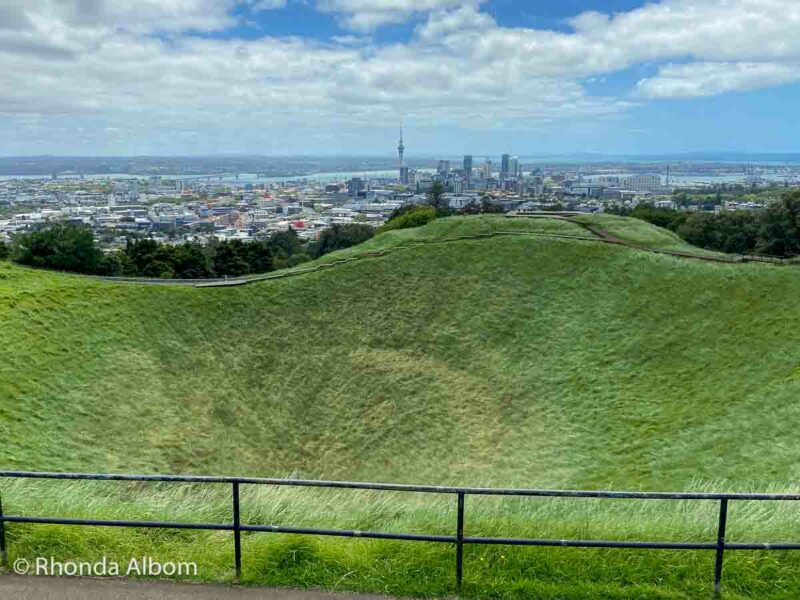 At the Mount Eden volcano summit overlooking the crater and the skyline of Auckland city