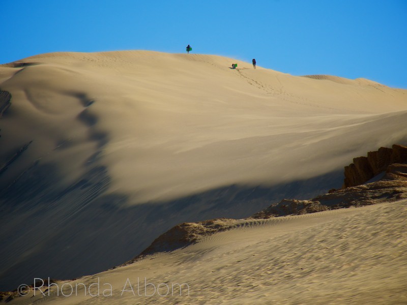 Our girls and their friend walking up the sand dunes as the wind blows.