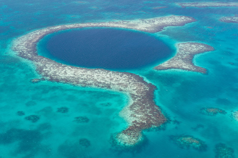 An aerial view of the coral reef and deep cave that make up the famous diving spot of the Blue Hole in the Caribbean Ocean off the coast of Belize.