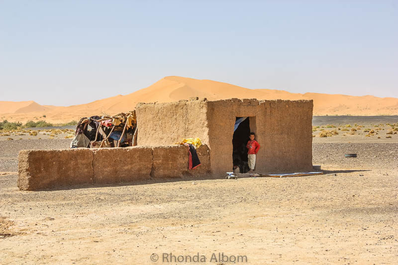 A boy stands in the doorway of one of the more solid structures at a Bedouin camp in the Sahara desert in Morocco