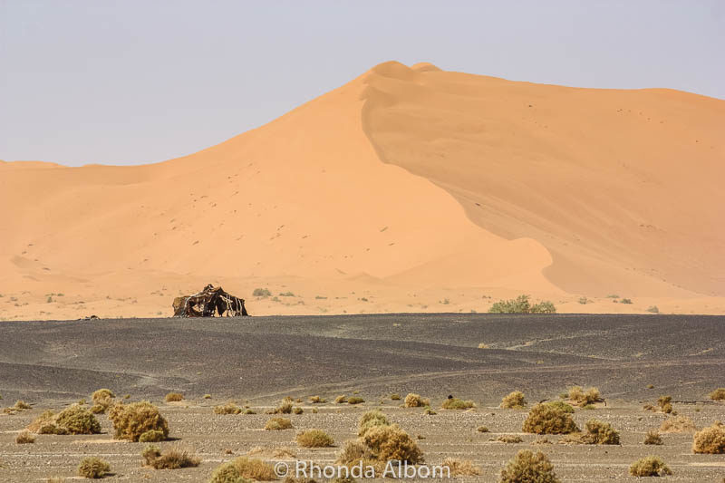 A Berber camp in the distance, at the base of the sand dunes in the Sahara desert in Morocco