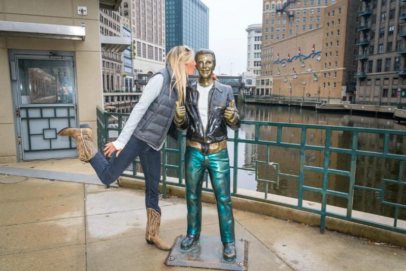 Travel blogger posing with statues of the Fonze in Milwaukee Wisconson Usa
