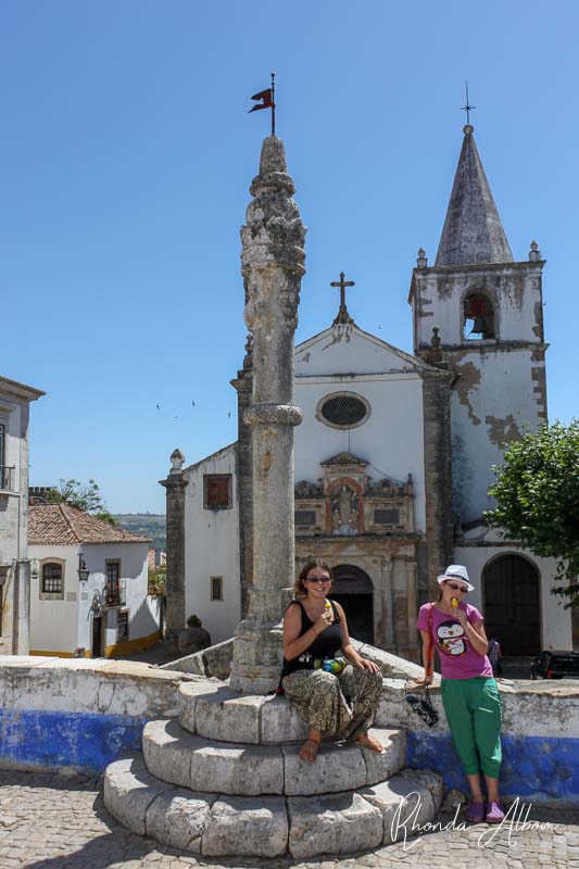14 Things to Do in Obidos Portugal - a Medieval Delight 12 Girls eating ice cream with St Mary's Church in the background