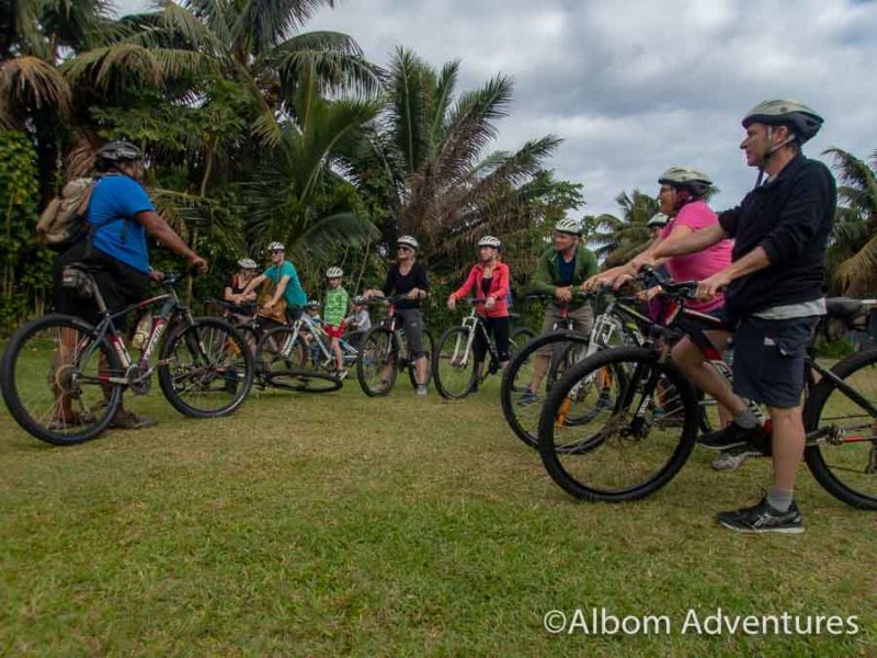 Our group on bicycles, wearing helmets and ready to to on a bicycle tour with Storytellers Eco-Cycle in Rarotonga