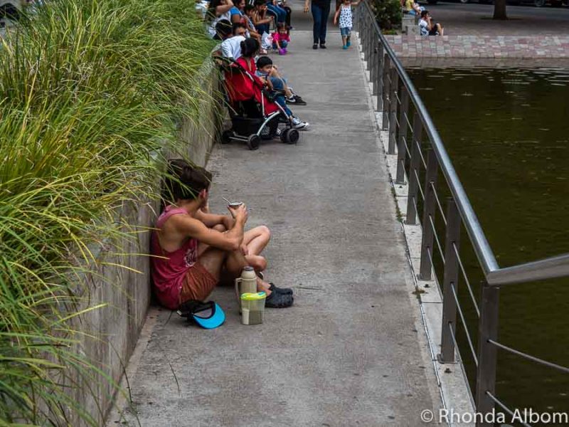 Friends sitting on the sidewalk and drinking maté at Paseo del Buen Pastor in Cordoba Argentina