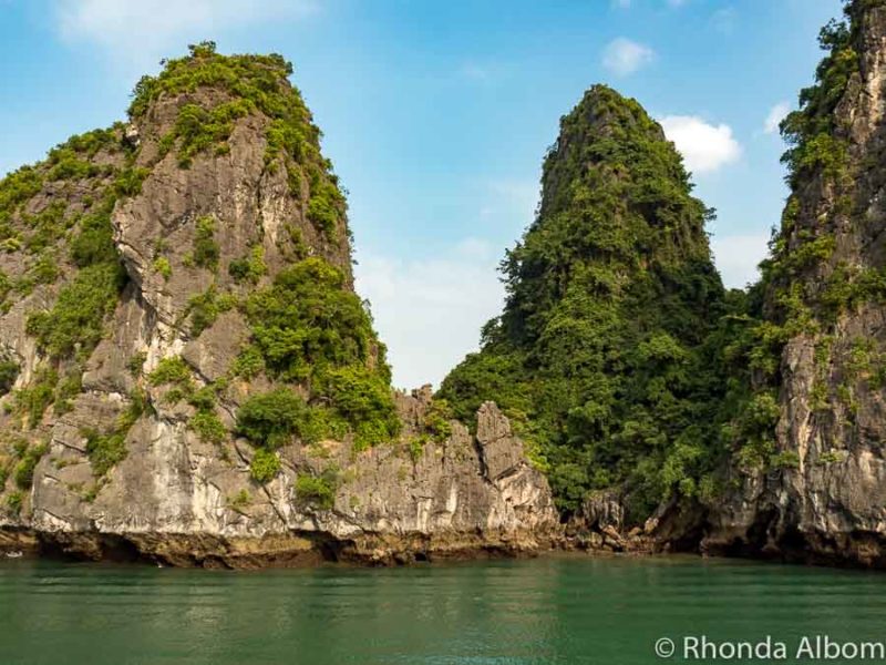 Towering limestone islands reaching up to the heavens from the emerald green waters in Vietnam