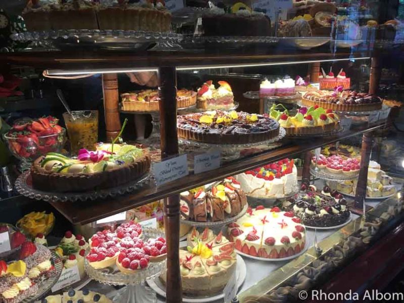 Fun Things to Do in Melbourne for Couples 4 Three shelves of cakes and other sweet desserts in the display case at Hopetoun Tea Rooms, part of the Melbourne cafe culture