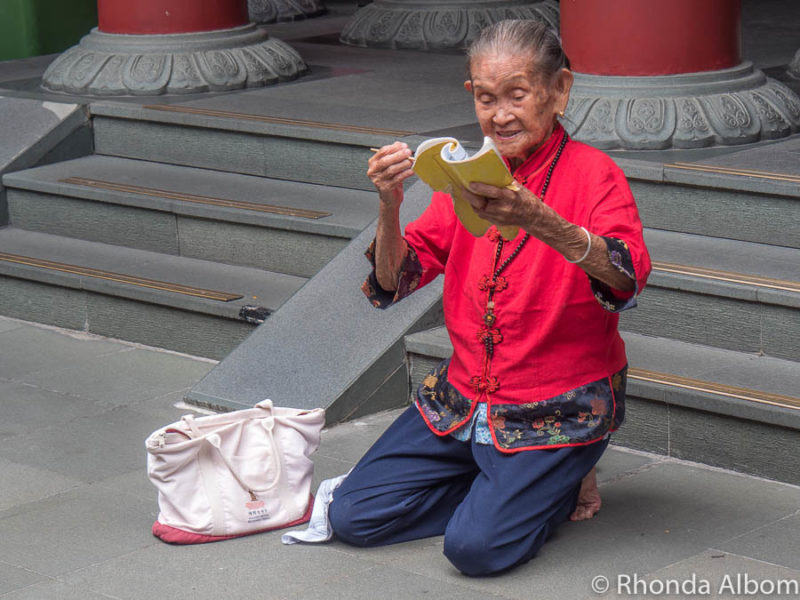 A woman praying outside the Buddha Tooth Relic Temple in Singapore.