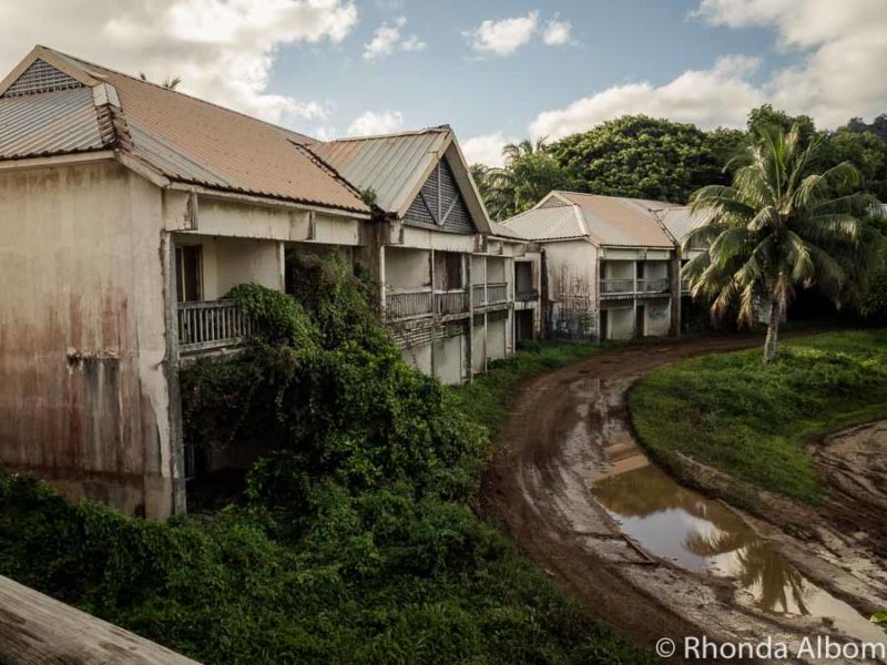 Sheraton Rarotonga: Abandoned Hotel with a Curse in the Cook Islands 7 Wet and muddy road passing in front of several derelict buildings of the abandoned Sheraton resort complex in the Cook Islands