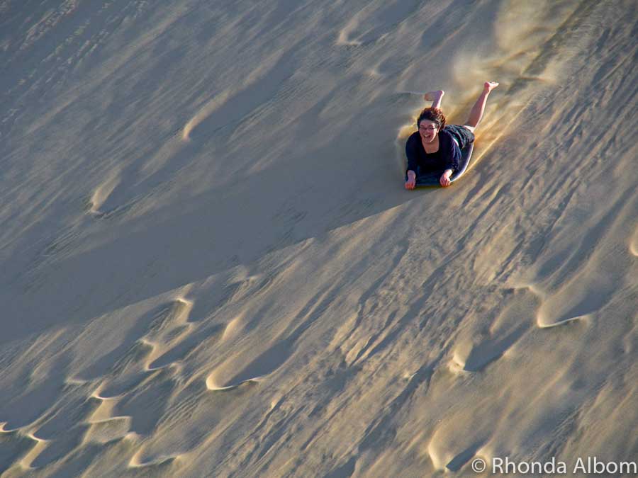A girl sandboarding New Zealand style - full speed down the Giant Te Paki Sand Dunes in Northland, New Zealand