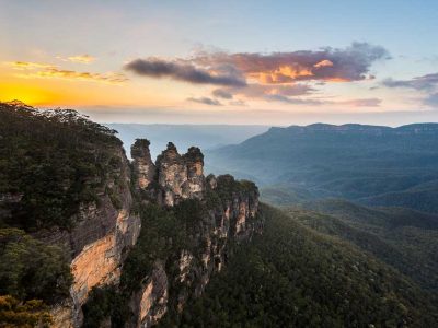 Rising sun illuminates the Three Sisters rock formation in the valley from Echo Point overlooking the majestic Blue Mountains, one of the popular day trips from Sydney