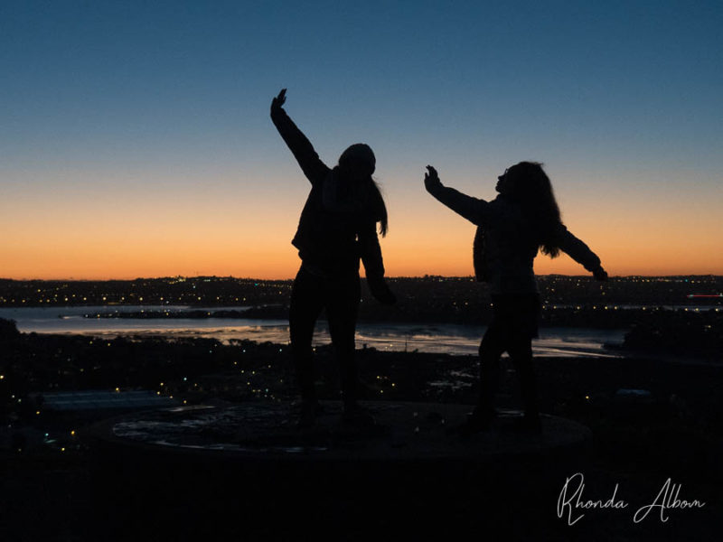 Mount Victoria Devonport: Best Views of Auckland Sunset and Skyline 3 Two girls posing larger than life and silhouetted against the colors of the sunset