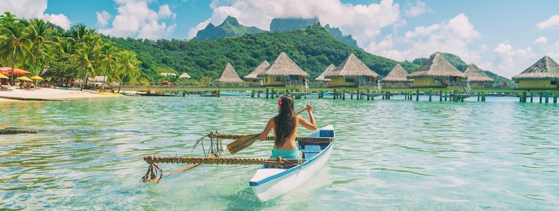 Women paddling in a French Polynesian outrigger canoe in Bora Bora