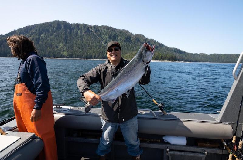 Man on a fishing boat holding a salmon he just caught