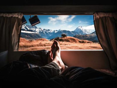 Lookout through the back window at the snowcapped mountains in the distance after renting a campervan in New Zealand.