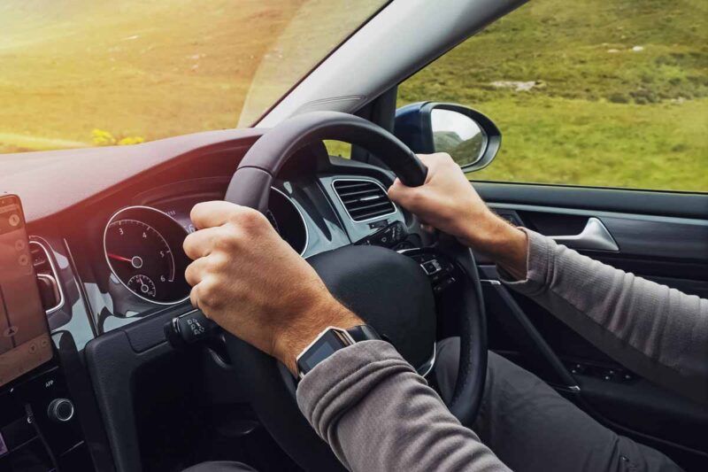 Person driving on the left hand side of the road, the steering wheel on the right.