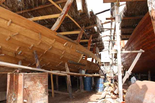 Craftsman hand building a traditional ship called a Dhow in Oman. Craftsman hand building a traditional ship called a Dhow in Oman.